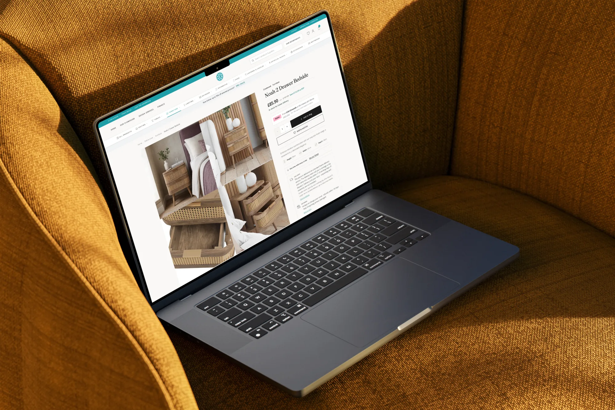 Laptop on a mustard armchair showing a Crestwood Interiors product page for the Noah 2 Drawer Bedside: centred logomark, Fraunces title, and Add to Bag