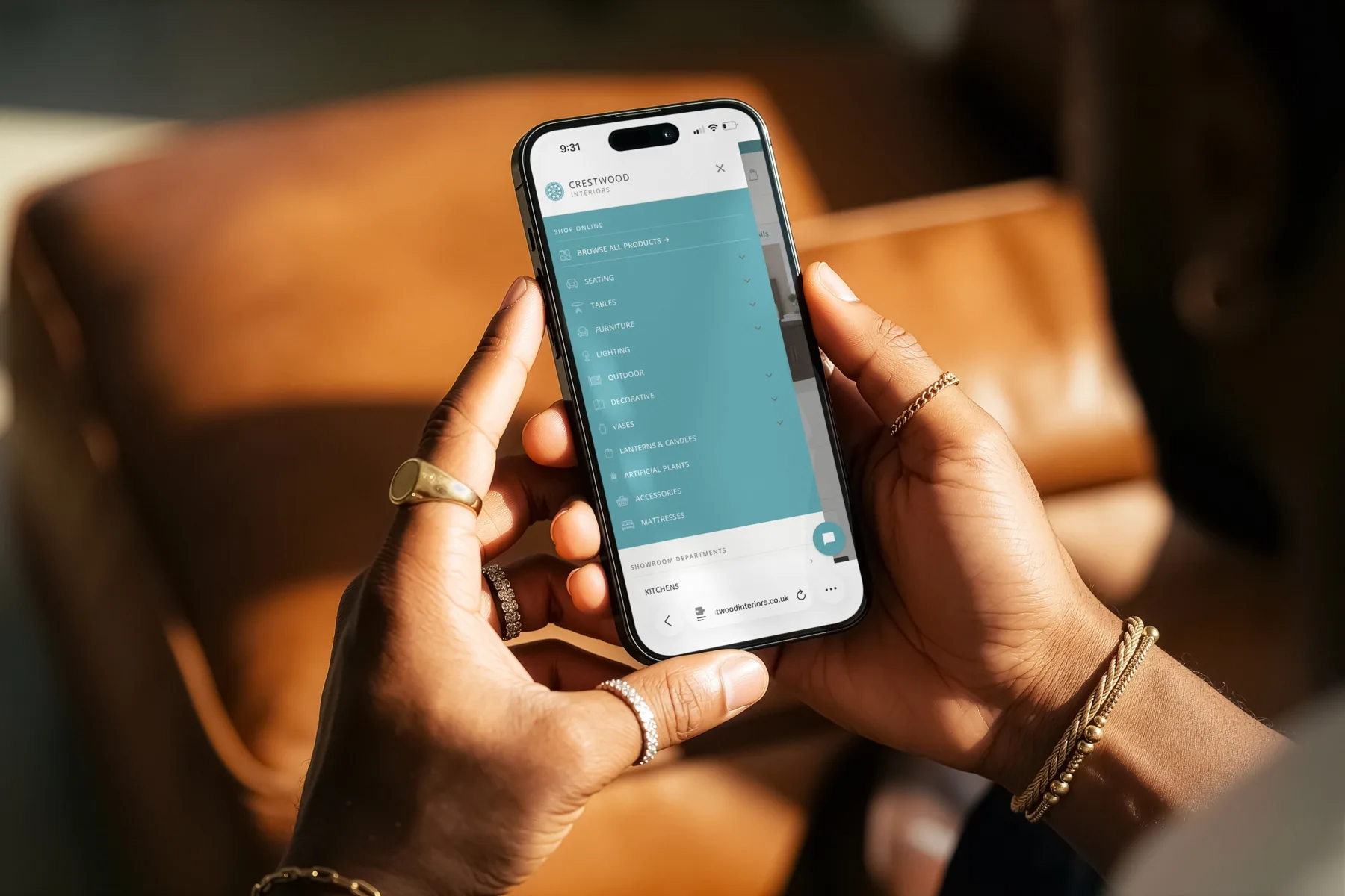 Hands holding a phone open to the Crestwood Interiors mobile menu: teal Shop Online panel with hand-drawn category icons, and showroom departments listed below